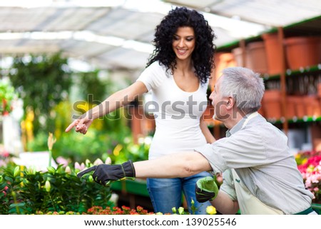 Woman pointing at flowers while asking advice to a gardener