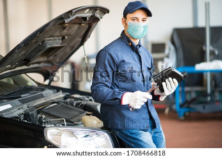 Masked car mechanic holding a jug of motor oil during coronavirus pandemic Foto stock © 