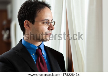 Young manager looking outside the window from his office