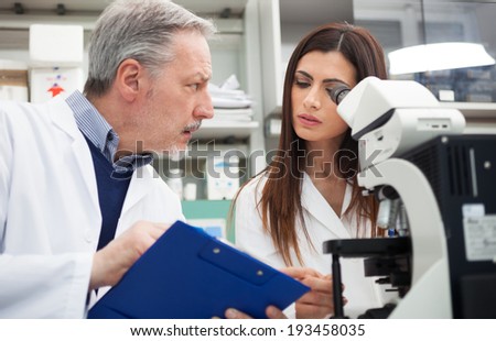 People using a microscope in a chemical laboratory