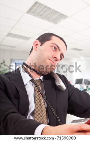 Young man strangling himself with a telephone cord in an office environment