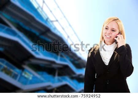 Blonde young woman on the phone with a glass building in the background
