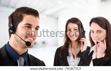 Portrait of a friendly phone operator. Two female operators in the bright and blurred background.