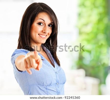 Portrait of a young smiling businesswoman pointing at you