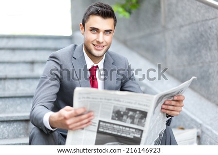 Business man reading a newspaper sitting on the stairs