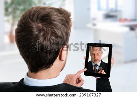 Business man using his tablet to speak to a colleague
