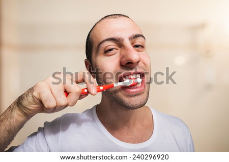 Funny man using a toothbrush to brush his teeth
