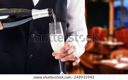 Portrait of a waiter pouring champagne into a flute