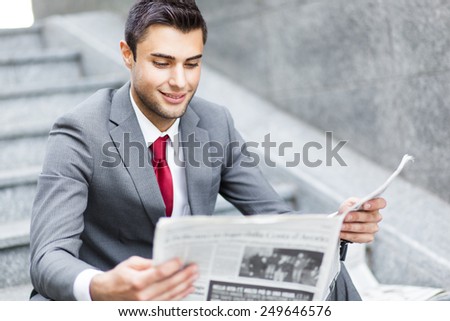 Business man reading a newspaper sitting on the stairs