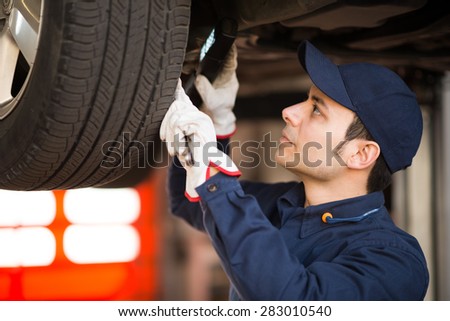 Mechanic using a lamp to inspect a lifted car