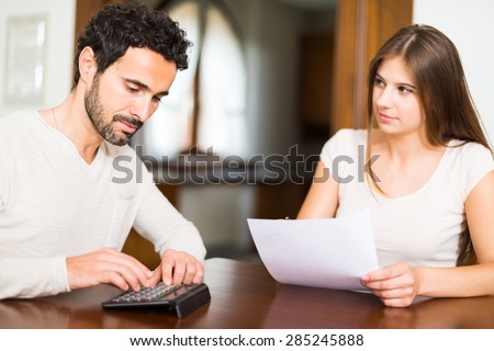 Young couple calculating their expenses. Shallow depth of field, focus on the man