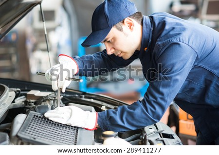 Portrait of an auto mechanic at work on a car in his garage