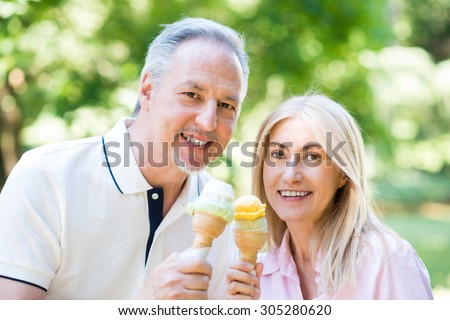 Portrait of an happy mature couple eating an ice cream in a park