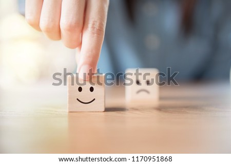 Close up customer hand choose smiley face and blurred sad face icon on wood cube, Service rating, satisfaction concept. 商業照片 © 