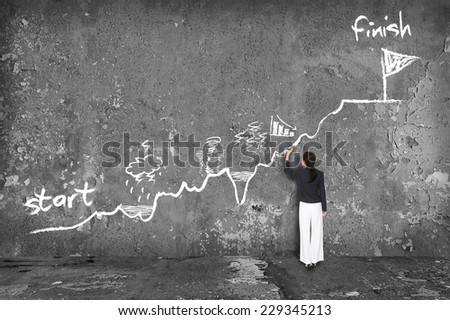 businesswoman drawing a way to success on the wall