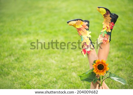 Sexy woman legs in autumn boots from fallen leaves. Happy autumn vacation concept