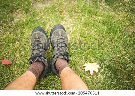 close up of feet of a runner relaxing after running in autumn leaves and and green grass