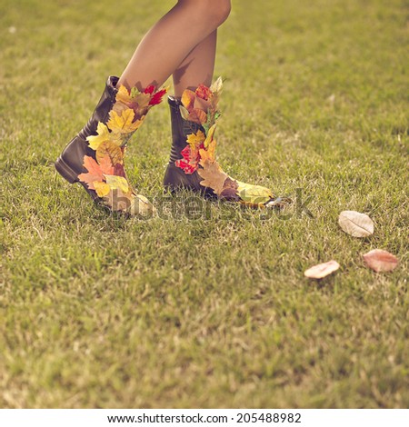 Sexy woman legs in autumn boots from fallen leaves. Happy autumn vacation concept. toned old vintage image