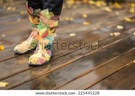 Autumn legs in funny boots made from fallen leaves