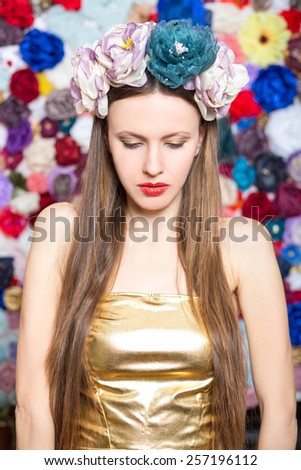 Sensual brunette lady with floral wreath on her head over handmade flower background