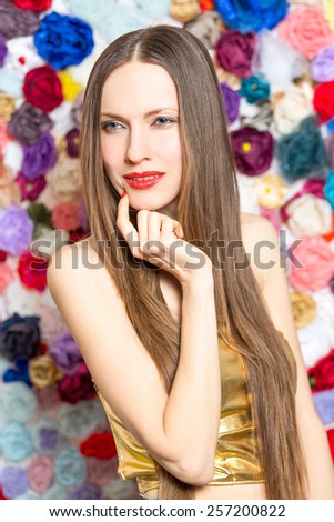 Sensual fashion woman over flower background wearing little golden dress