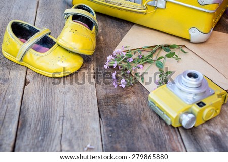 Romantic background with vintage things: camera, suitcase, old baby shoes, envelop with wild flowers over grunge brown background. selective focus