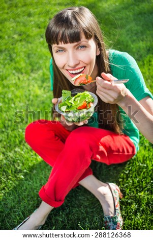 Close-up of pretty girl eating fresh vegetable salad, focus on eyes