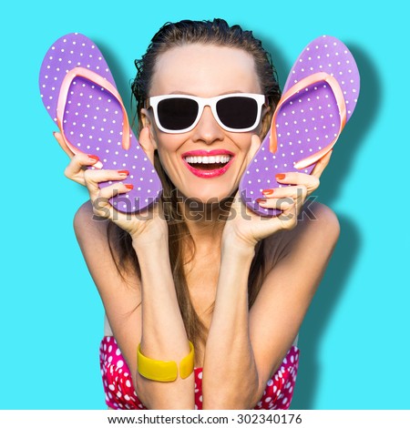 Happy playful girl with flip flops wearing sunglasses. Cheerful woman enjoy her vacation have fun
