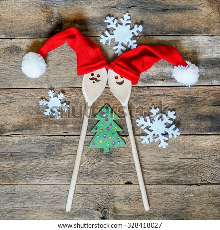 Funny wooden christmas background for a menu card with wooden spoons wearing funny christmas hats. creative idea