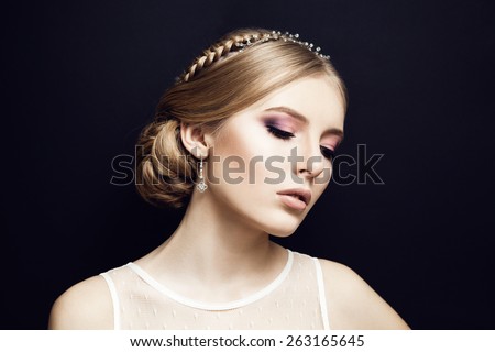 Portrait of beautiful bride at wedding dress in studio. Newlywed woman. Dark background. Lights makeup and braid hairstyle. Closed eyes.