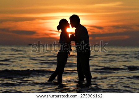Sunset silhouette of young couple in love at beach in summer holiday