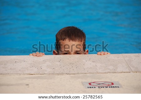 Boy peeking over the side of a pool