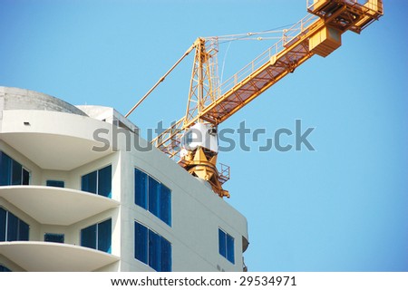 Yellow crane on the top of a building under construction close up