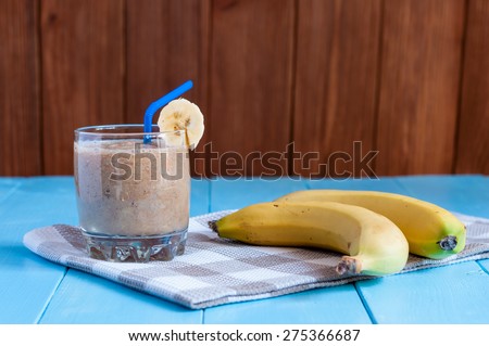 Healthy homemade Chocolate banana smoothie in glass and fresh bananas on wooden background. Weight loss, healthy food, diet and detoxification