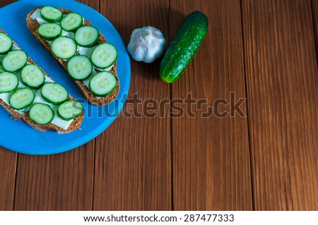 Freshly sandwich with sliced cucumbers and garlic with cucumber in rural or rustic kitchen at vintage wood table from above. Background with empty space for text