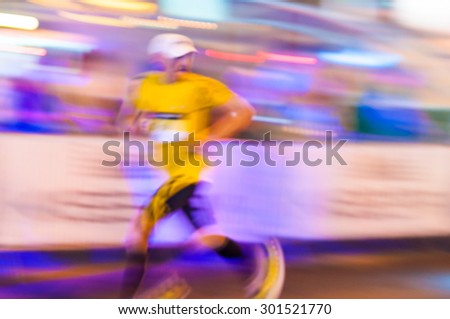 Blurred runner athlete running at night marathon. Man fitness silhouette evening jogging workout wellness concept