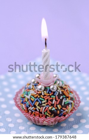 Lit birthday candle on colorful background