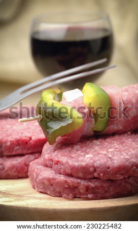 Raw hamburgers with glass of red wine