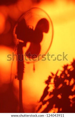 Electric fan shadow among orange wall. Heat and coolness concept. Cool theme background for summer advertising