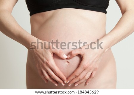 a pregnant woman forming a heart on her tummy with her hands