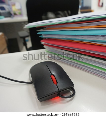Computer mouse and document folder placed on desk at office.