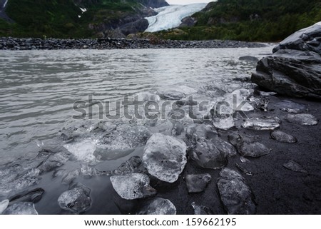 Ice chunks cover beach like boulders and pebbles on river near end of glacier in Alaska