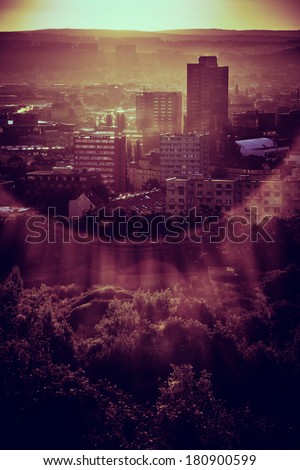 Sun rising from behind a hill over a part of large city
