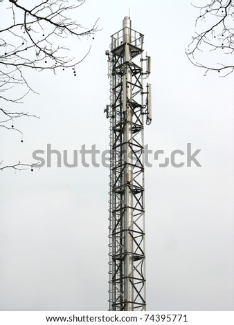 Metallic communication tower with antennas and ladder over sky background