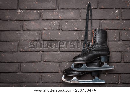 Old Black Figure Ice Skates Hanging On A Brick Wall