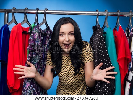 Happy Woman At The Clothing Rack With Dresses On Blue Background