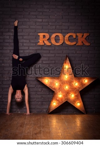 Beautiful Girl Doing Yoga Exercises Near Iron Star Leaning On Brick Wall