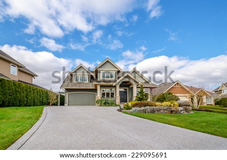 Luxury house with a two-car garage and beautiful landscaping on a sunny day. Home exterior.