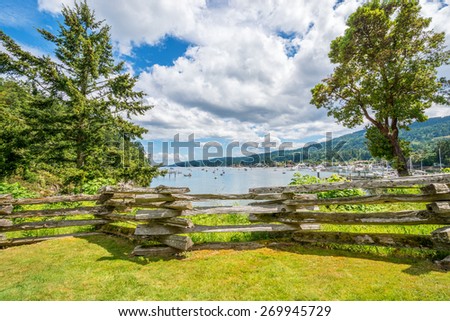 Rustic wood fence on a green field with the sea in the background.