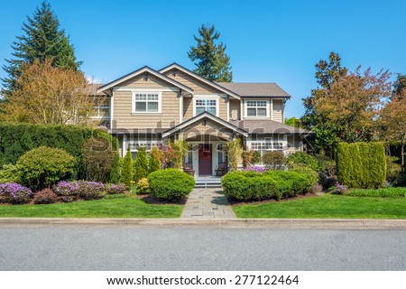 Luxury house with nicely trimmed front yard, lawn in a residential neighborhood. Home exterior.